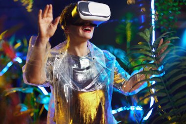 smiling trendy woman in virtual reality in vr headset exploring.