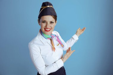 Mutlu stil sahibi hostes kadın üniformalı, mavi arka planda izole edilmiş..