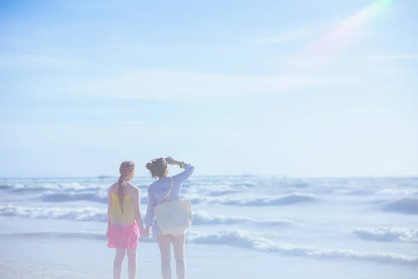 遠くを見ているビーチでスタイリッシュな母親と子供の後ろから見た — ストック写真