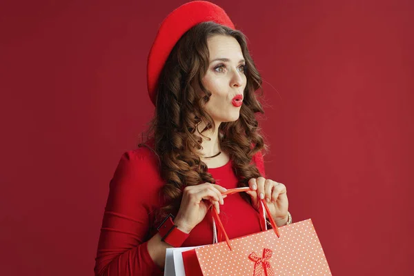 ハッピーバレンタイン 赤のドレスとベレー帽のスタイリッシュな女性はショッピングバッグで赤い背景に隔離され — ストック写真
