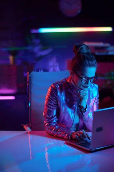 未来的な概念を嫌悪するネオン 現代のオフィスでノートパソコンを使用して眼鏡で高価なエレガントなビジネス女性 — ストック写真