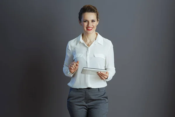 基于灰色背景的平板电脑应用程序 让穿着白衬衫的中年妇女快乐而时尚 — 图库照片