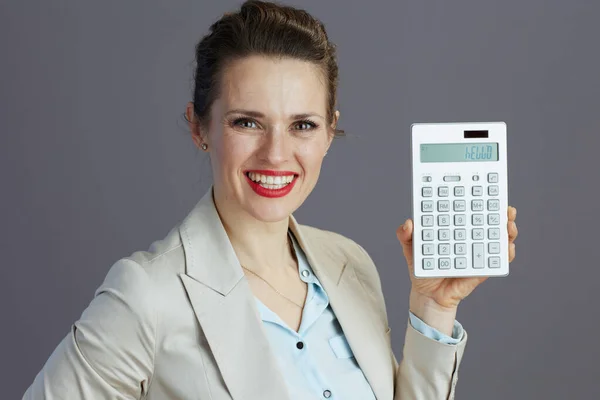 穿着浅色西装 头戴灰色背景计算器的40岁现代女性员工面带微笑 — 图库照片