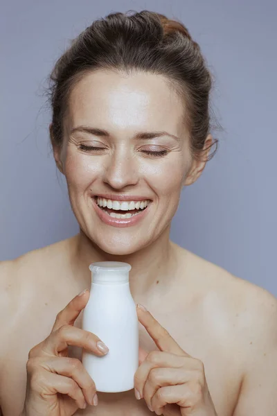 Glimlachende Jonge Vrouw Met Cosmetische Crème Pot Geïsoleerd Blauw — Stockfoto