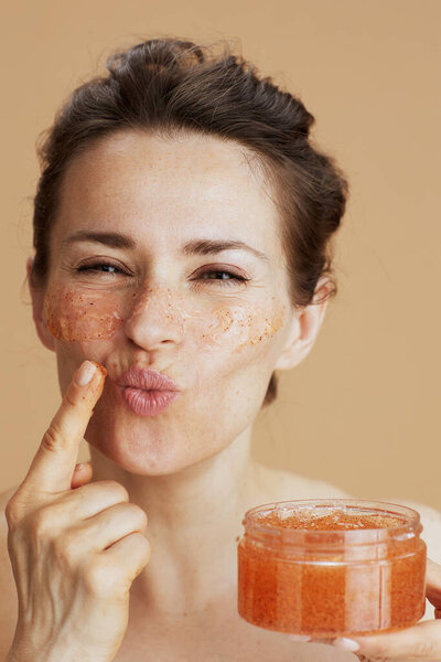 молодая женщина с лицом скраб на бежевом фоне.