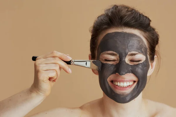 Sorrindo Mulher Moderna Com Escova Máscara Facial Isolada Fundo Bege — Fotografia de Stock