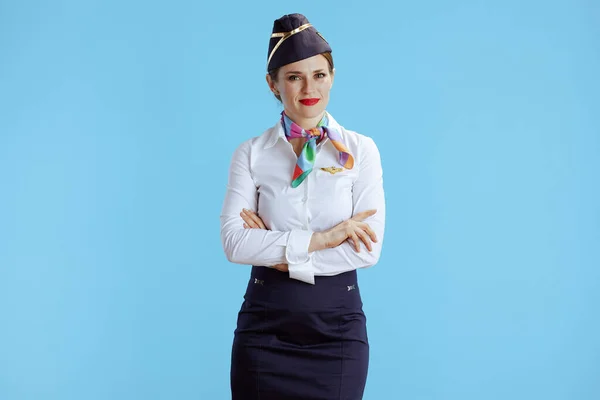 elegant air hostess woman against blue background in uniform.
