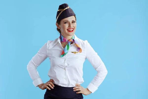 stock image happy stylish flight attendant woman against blue background in uniform.