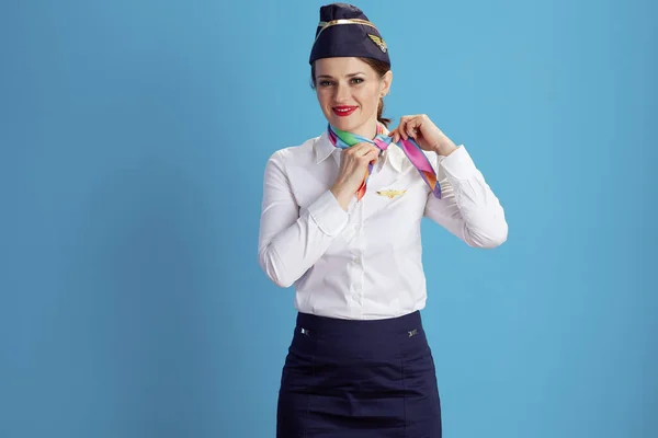 快乐时尚的空姐 穿着制服调整围巾 被蓝色背景隔离 — 图库照片
