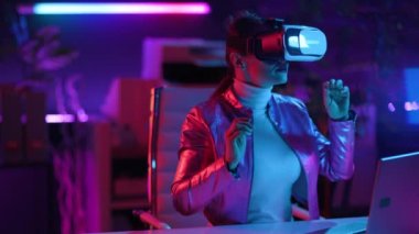 Neon metaverse futuristic concept. curious stylish business woman in virtual reality goggles in modern office.