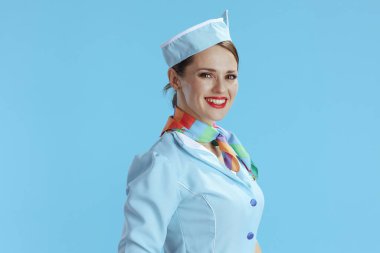Mavi üniformalı, mavi arka planda izole edilmiş, gülümseyen modern uçuş görevlisi kadın..