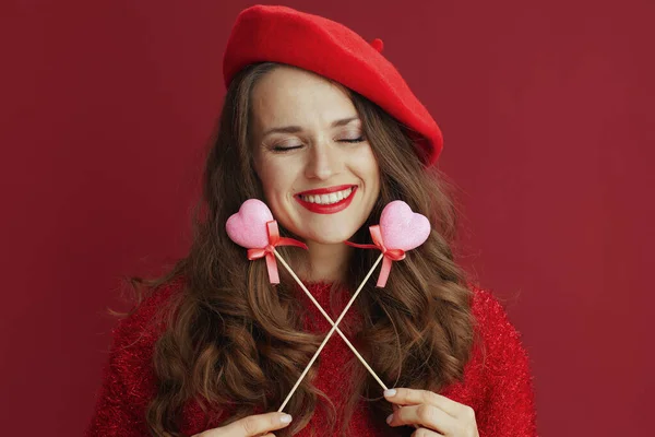 ハッピーバレンタイン リラックスした現代的な中年女性で赤いセーターとベレー帽に心付きスティック — ストック写真