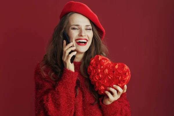 ハッピーバレンタイン 赤いセーターに赤いハートのベレー帽を着た幸せな流行の女性がスマートフォンで話しています — ストック写真