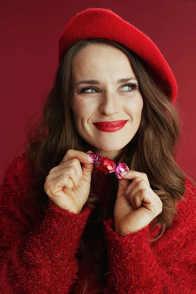 ハッピーバレンタイン 赤いセーターにベレー帽のスタイリッシュな女性にキャンディ — ストック写真