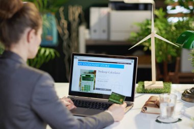 Modern ofisteki e-ticaret sitesinde bilgisayar ve kredi kartı ile online alışveriş yapan modern bir kadının arkasında görüldü..