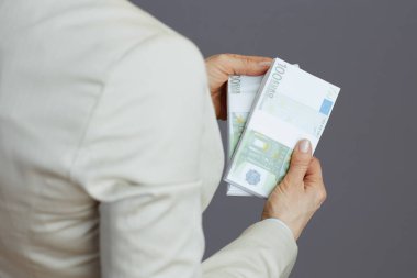 Küçük işletme sahibi kadına yakın plan. Hafif bir iş elbisesi içinde. Avro para paketleri gri renkte..