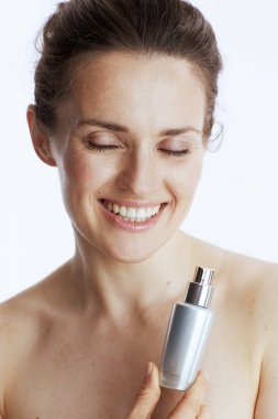 Beyaz arka planda izole edilmiş kozmetik krem kavanozu olan 40 yaşında mutlu bir kadın..