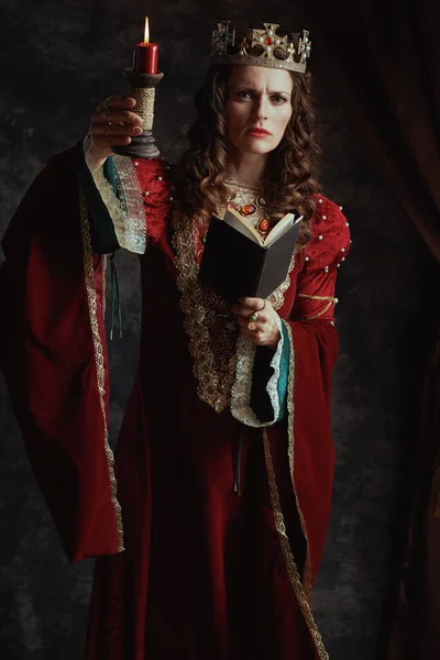 全长的中世纪女王画像 红色衣服 蜡烛和深灰色背景的皇冠 — 图库照片