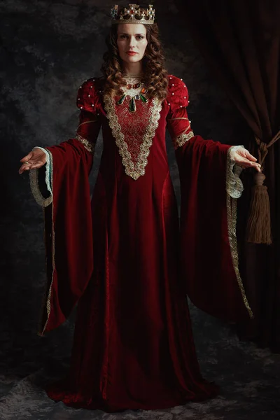 Ortaçağ Kraliçesinin Koyu Gri Arkaplanlı Kırmızı Elbiseli Tam Boy Portresi — Stok fotoğraf