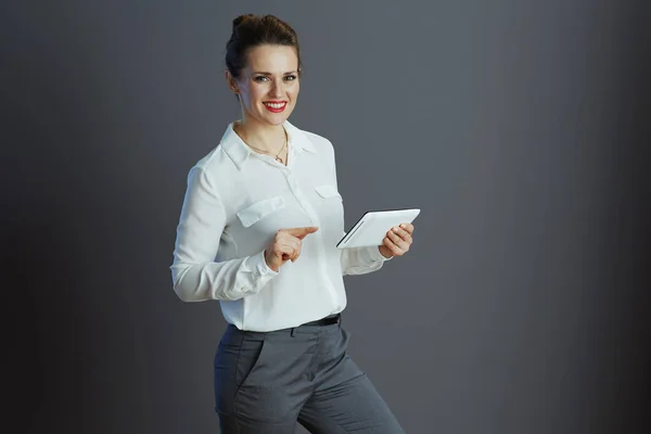 在平板电脑上使用灰色背景的应用程序 对穿着白衬衫的现代中年小企业主女人微笑 — 图库照片