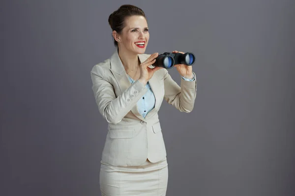 穿着浅色西服 头戴灰色背景双筒望远镜的中年妇女 — 图库照片