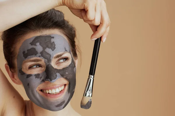 面带微笑的现代40岁女人 带着用米色背景隔开的刷子和化妆品面具 — 图库照片