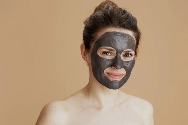 具有米色背景的化妆品面具的年轻女性 — 图库照片