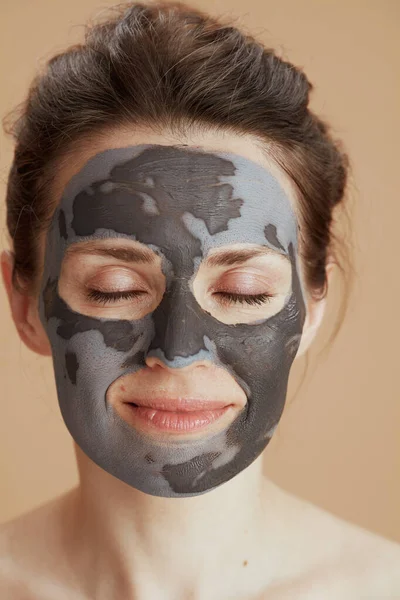 ベージュ地に隔離された美容マスクを持つリラックスした現代的な中年女性 — ストック写真
