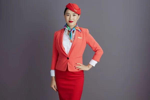 穿着红色短裙 夹克和帽子制服的现代亚洲女空姐 灰色背景隔离 — 图库照片