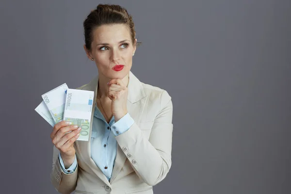 灰色の背景にユーロのお金パックと軽いビジネススーツの高価なスタイリッシュな女性従業員 — ストック写真
