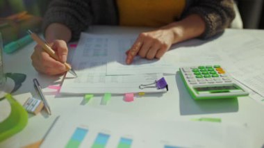 Hesap makinesi ve evrakları olan muhasebeci kadın ofiste çalışıyor..