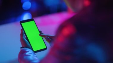 Neon metaevren fütüristik konsepti. Akıllı telefonlu, boş yeşil ekranlı modern iş kadını.
