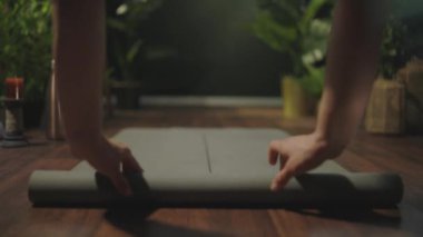 Closeup on middle aged woman with yoga mat folding mat in the green house.