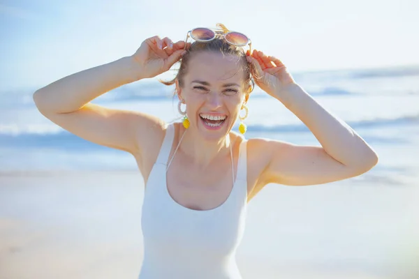 笑顔の肖像画エレガントな40歳の女性で白い水着でビーチ楽しい時間を持っています — ストック写真