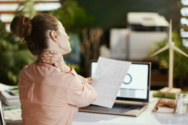 現代のオフィスで首の痛みを持つ文書やラップトップを持つ現代のビジネス女性の後ろから見た — ストック写真