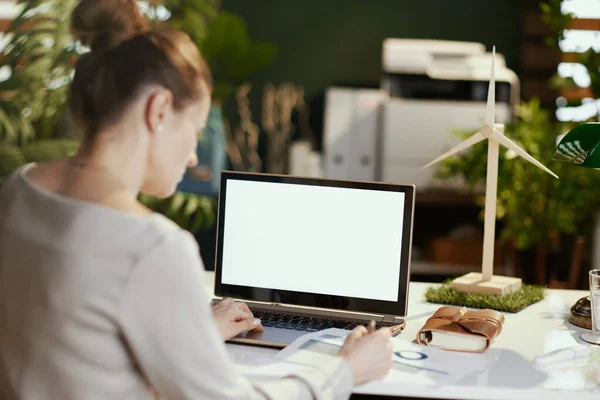 現代のオフィスで文書やノートパソコンの空白の画面を持つ現代のビジネス女性の後ろから見た — ストック写真