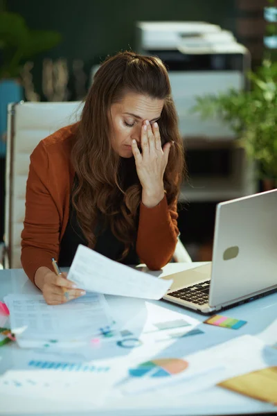 ストレスの多い現代的な中年中小企業の所有者の女性ノートパソコンで作業文書と現代の緑のオフィス — ストック写真