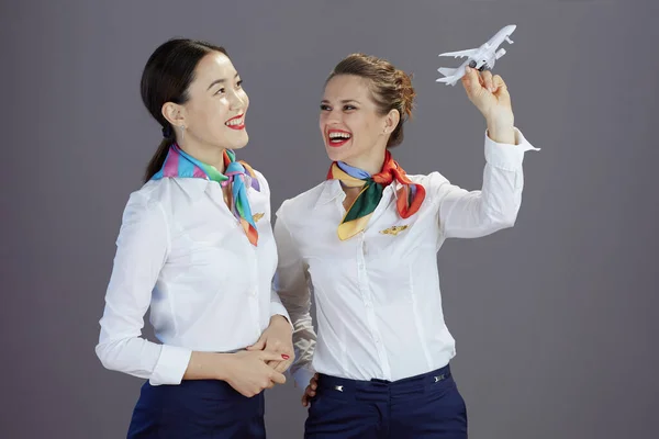 穿着蓝色短裙 白衬衫 头戴灰色背景的小飞机的女乘务员们微笑着 — 图库照片