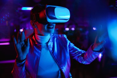 Neon metaevren fütüristik konsepti. Modern ofiste sanal gerçeklik teknolojisi kullanan 40 yaşında mutlu bir kadın..