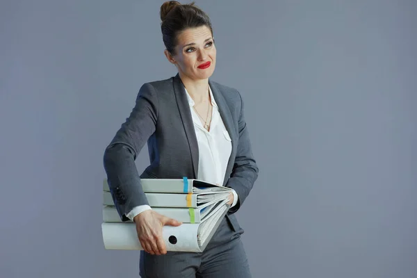 强调40岁的现代女性雇员穿着灰色西装 有灰色背景的文件夹 — 图库照片