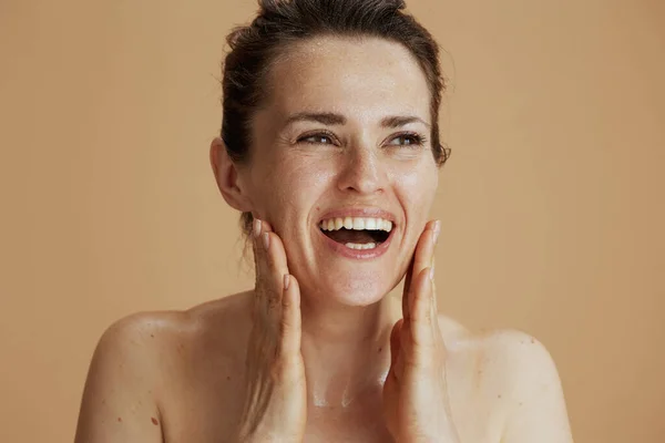 Uśmiechnięta Młoda Kobieta Mokrą Twarzą Myjąca Się Beżowym Tle — Zdjęcie stockowe