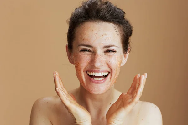 Sonriente Mujer Moderna Con Exfoliante Facial Sobre Fondo Beige — Foto de Stock