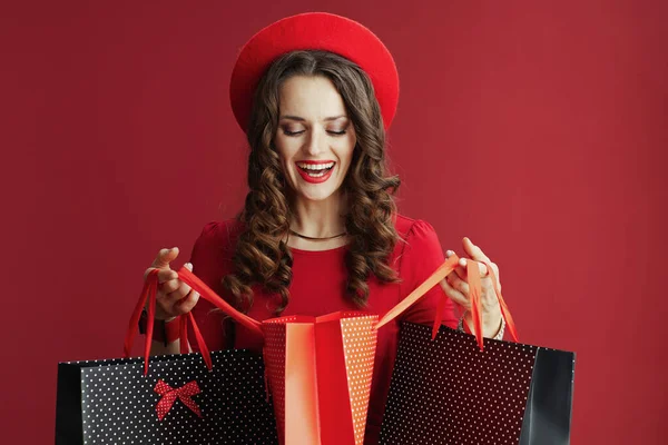 情人节快乐 穿着红色衣服 戴着红色背景的贝雷帽 头戴购物袋的快乐中年妇女 — 图库照片