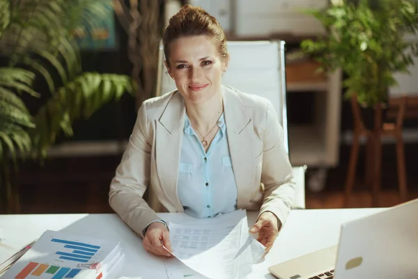 幸せな現代の肖像40歳の女性従業員で文書と現代の緑のオフィスで軽いビジネススーツ — ストック写真