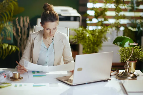 高価な現代40歳の小さなビジネスの所有者の女性文書やノートパソコンと現代の緑のオフィスで軽いビジネススーツ — ストック写真