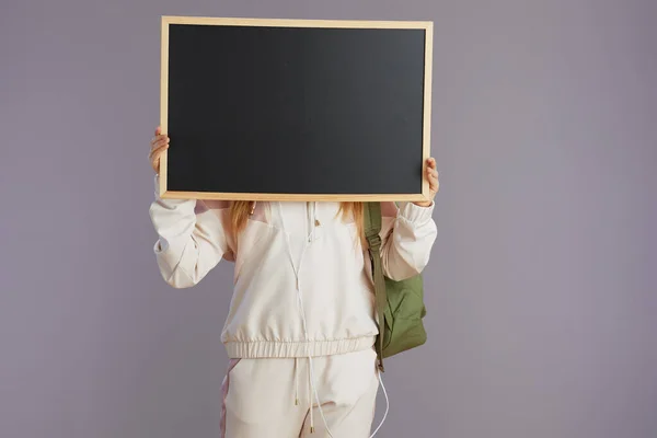 Trendy School Girl Beige Tracksuit Backpack Showing Blank Board Isolated — Stock Photo, Image