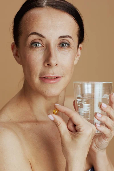 Moderne Frau Mit Glas Wasser Und Tablette Auf Beigem Hintergrund — Stockfoto