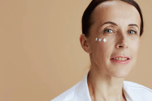 Moderní Žena Oční Krém Obličeji Béžovém Pozadí — Stock fotografie