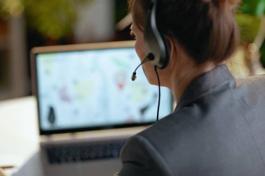 Dizüstü bilgisayarı ve kulaklığı olan modern kadına yakın çekim..