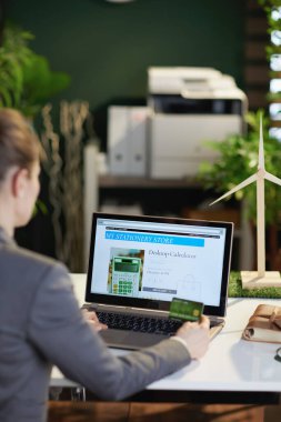 Modern ofisteki bilgisayar ve kredi kartı takibi yapan modern bir iş kadınının arkasında görülmüş..